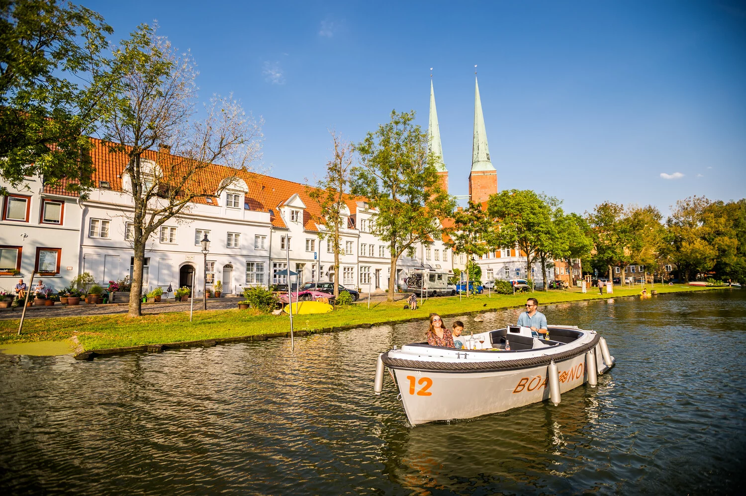 Eine Familie, bestehend aus Mutter, Vater und Sohn, im Elektroboot auf der Trave in Lübeck